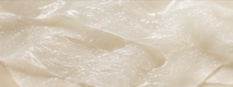 Pearl-clear translucent skincare film with soft luminous folds.