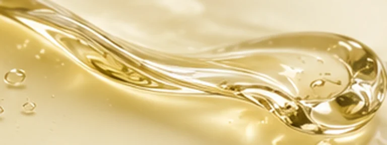 Golden translucent cleansing oil flowing in a smooth reflective ribbon.