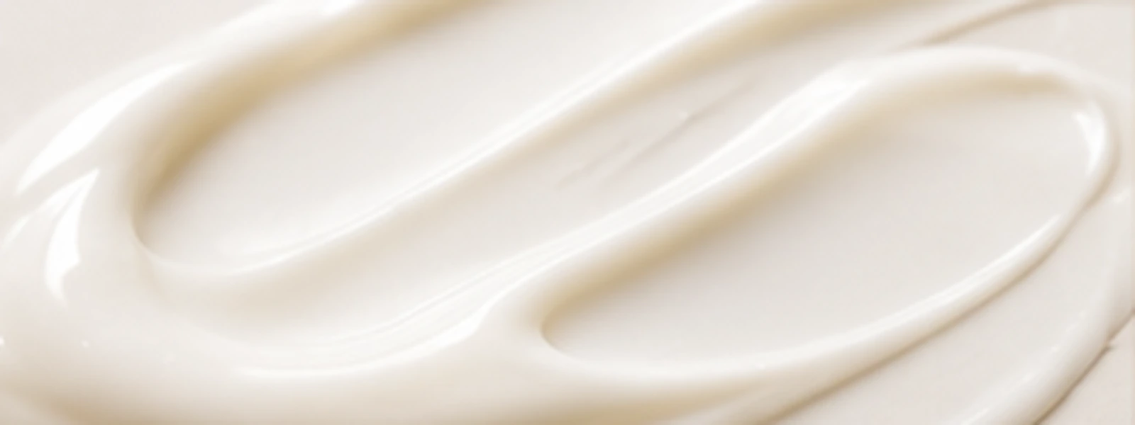 Soft ivory sunscreen cream in a clean flowing macro texture.
