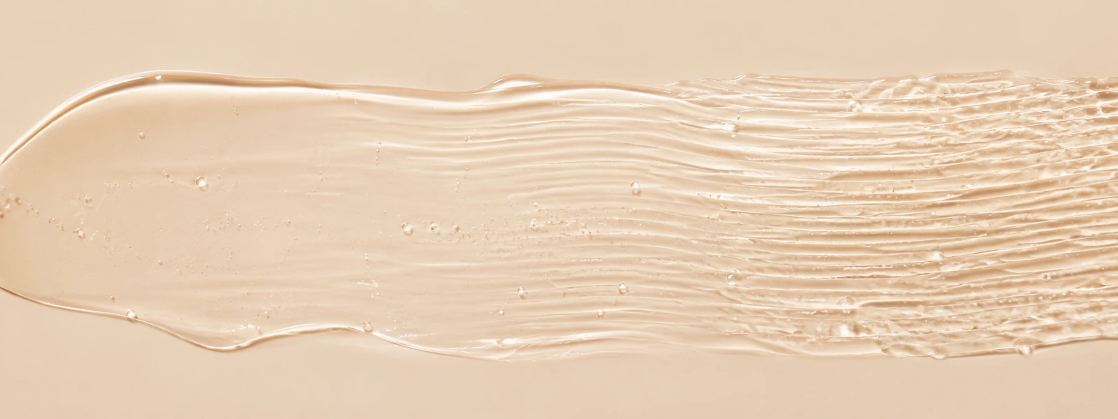 Clear skincare gel with fine soft ripples increasing in density across a warm ivory background.