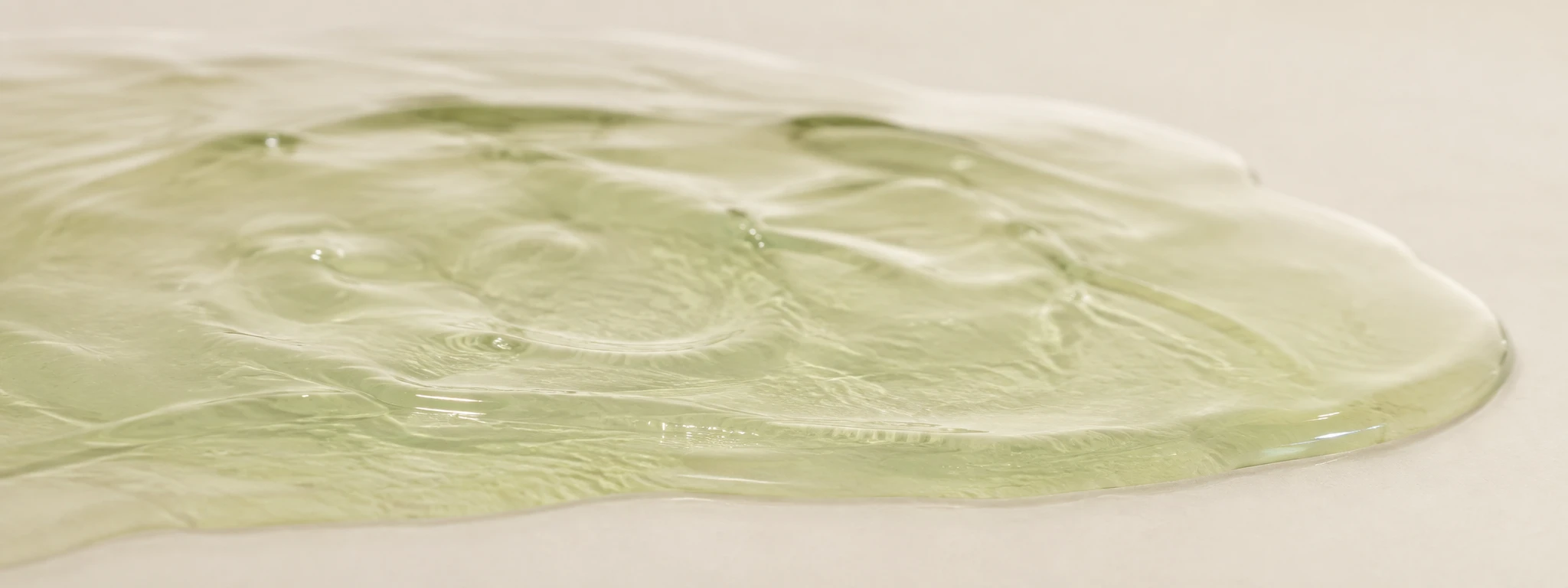 Minimal green centella gel pooled smoothly, calm macro skincare texture.