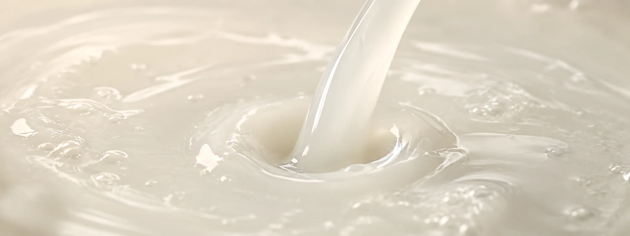 Pale, softly cloudy milky-white liquid pouring into a small pool, rice-water texture.