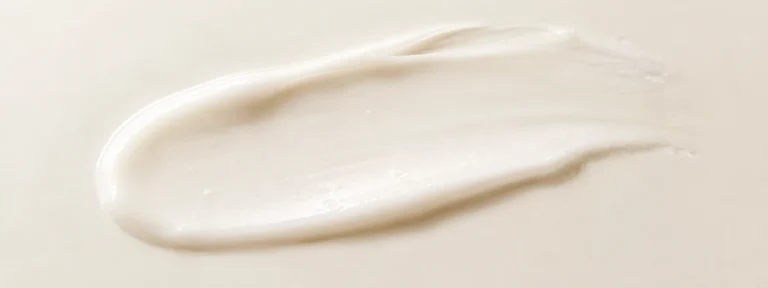 Soft white cream swiped in a gentle minimal smear on an ivory background.
