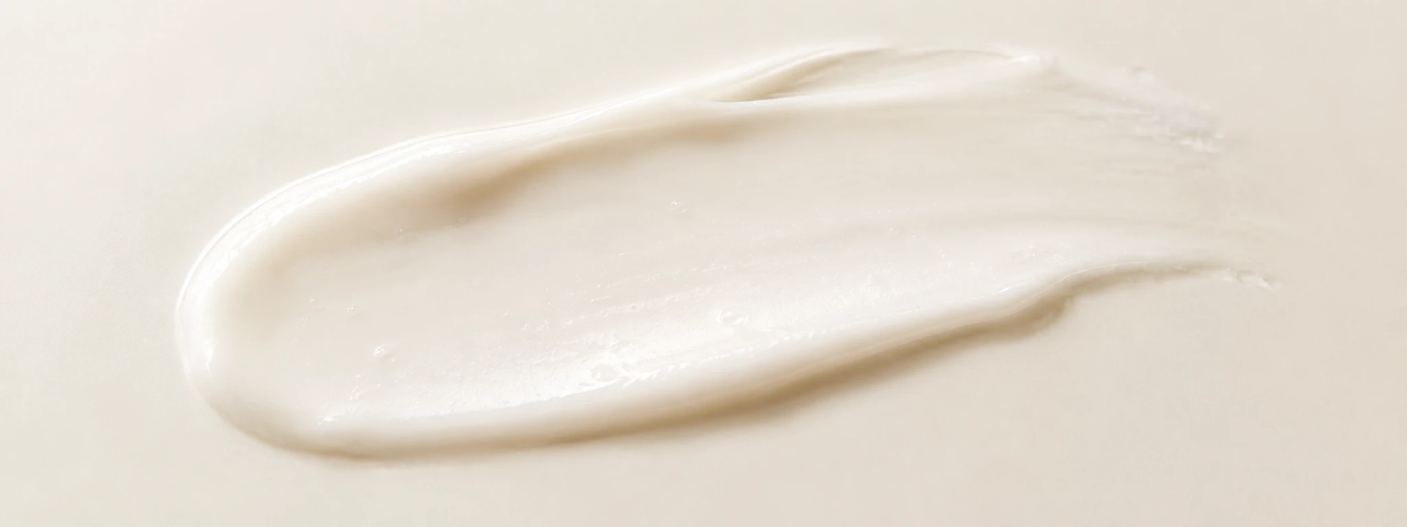 Soft white cream swiped in a gentle minimal smear on an ivory background.