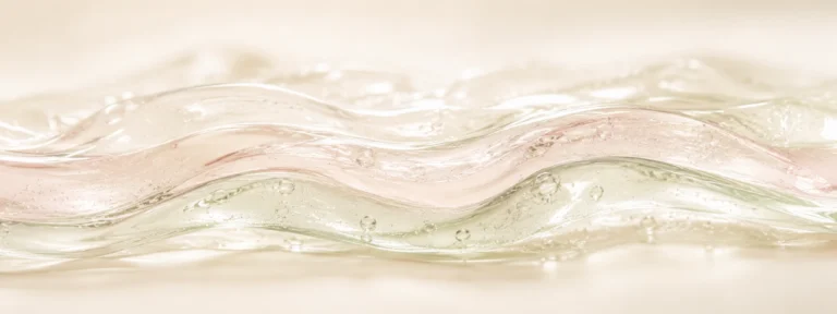 Three translucent ribbon layers in sage, blush, and ivory tints folding together, representing layered skincare textures.